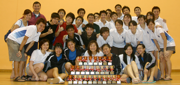 A large Fencing Masters squad gathered behind a pyramid of around twenty trophies